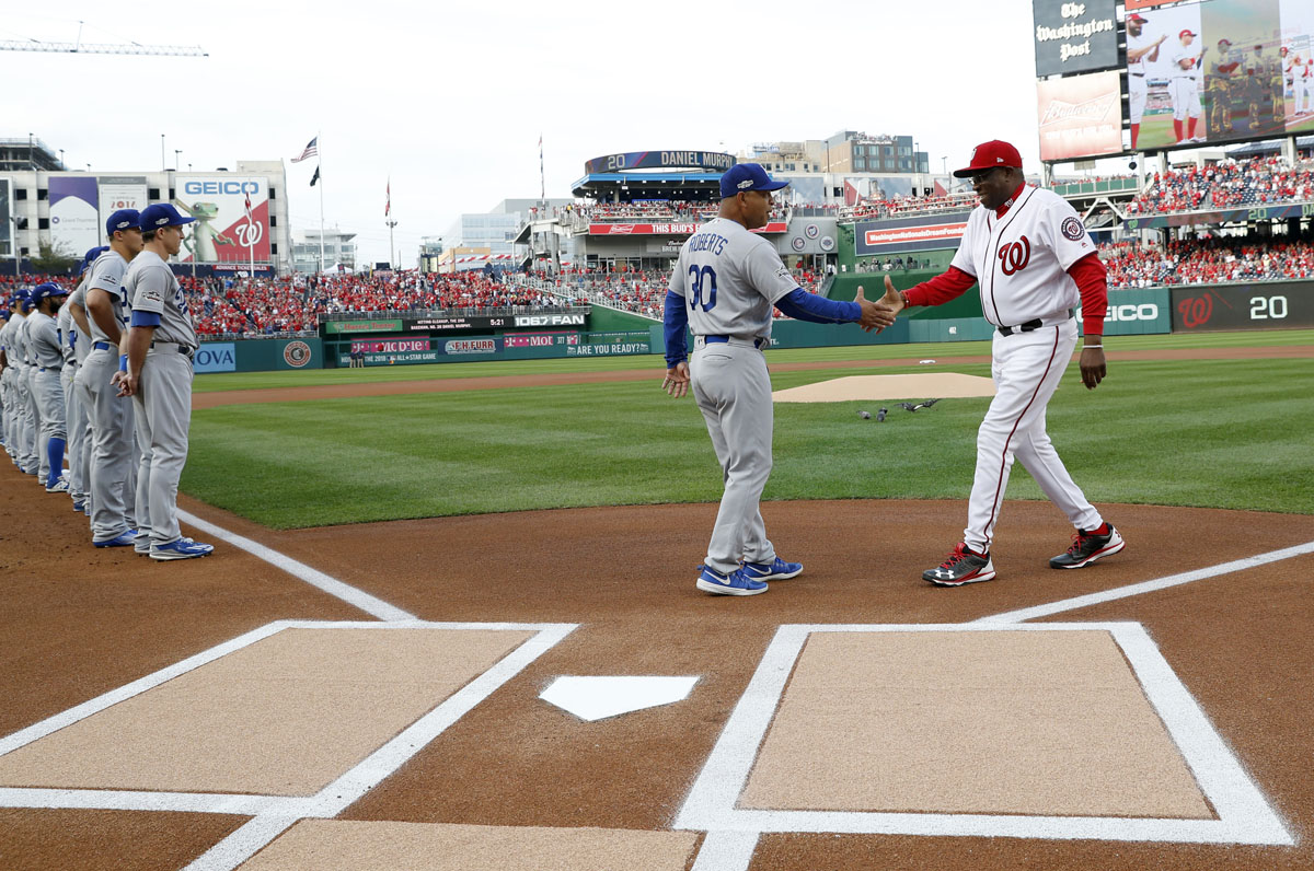 Los Angeles Dodgers manager Dave Roberts, left, and Washington Nationals manager Dusty Baker shake hands during introductions before Game 1 of baseball's National League Division Series, at Nationals Park, Friday, Oct. 7, 2016, in Washington. (AP Photo/Alex Brandon)