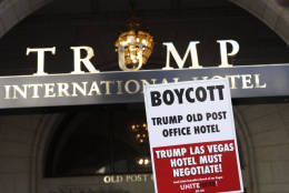 A protester holds up a sign at the Trump Interational Hotel opening Oct. 26. (WTOP/Kate Ryan)
