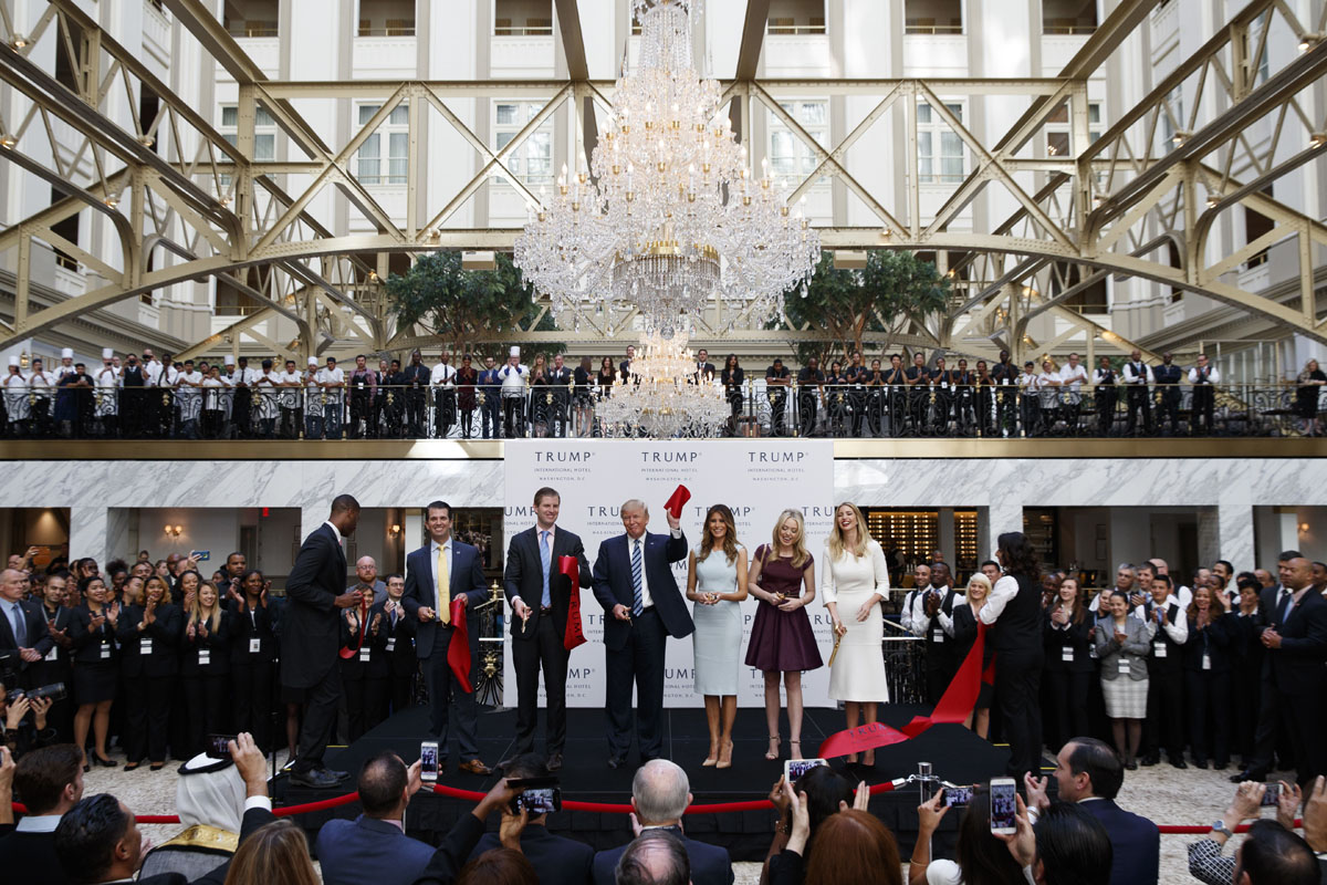 Republican presidential candidate Donald Trump, accompanied by, from left, Donald Trump Jr., Eric Trump, Trump, Melania Trump, Tiffany Trump and Ivanka Trump, holds up a ribbon during the grand opening ceremony of the Trump International Hotel- Old Post Office, Wednesday, Oct. 26, 2016, in Washington. (AP Photo/ Evan Vucci)