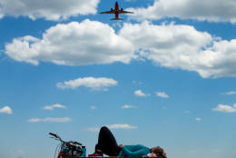 A plane takes off from Washington's Ronald Reagan National Airport as Julia Hurley of Washington relaxes on a picnic table at Gravelly Point Park in Arlington, Va., Wednesday, June 8, 2016, after bicycling to Mt. Vernon and back. (AP Photo/Andrew Harnik)