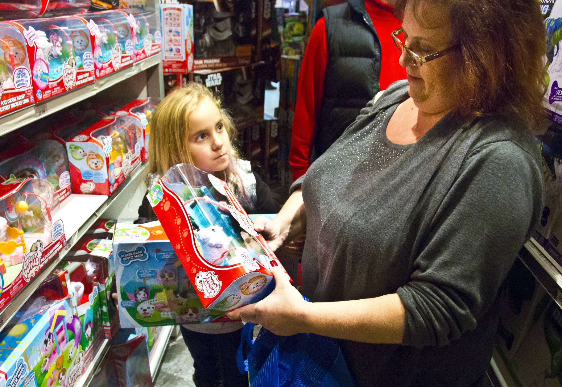 FILE - In this Friday, Nov. 27, 2015, file photo, Cinnamon Boffa, right, from Bensalem, Pa., checks out a "Chubby Puppies" toy for her daughter Serenity, left, at a Toys R Us, in New York. Toys R Us said Wednesday, Sept. 14, 2016, it has begun taking applications for part-time seasonal jobs in stores and distribution centers. A spokeswoman declined to give a nationwide figure but said the retailer expects to add at least 10,900 workers in five of its biggest markets: New York, Los Angeles, Philadelphia, Chicago and Washington. (AP Photo/Bebeto Matthews, File)