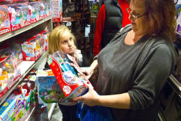 FILE - In this Friday, Nov. 27, 2015, file photo, Cinnamon Boffa, right, from Bensalem, Pa., checks out a "Chubby Puppies" toy for her daughter Serenity, left, at a Toys R Us, in New York. Toys R Us said Wednesday, Sept. 14, 2016, it has begun taking applications for part-time seasonal jobs in stores and distribution centers. A spokeswoman declined to give a nationwide figure but said the retailer expects to add at least 10,900 workers in five of its biggest markets: New York, Los Angeles, Philadelphia, Chicago and Washington. (AP Photo/Bebeto Matthews, File)
