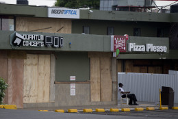 A security guard sits next to a several stores that had their windows covered with plywood in preparation for the arrival of Hurricane Matthew in Kingston, Jamaica, Monday, Oct. 3, 2016. Major Hurricane Matthew is slowly churning northward across the Caribbean and meteorologists say the powerful storm is expected to approach Jamaica and southwest Haiti by Monday night. (AP Photo/Eduardo Verdugo)