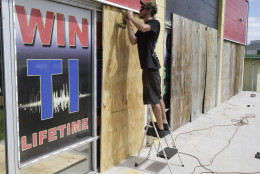 Chris Ramsey installs plywood panels over windows at a auto stereo and window tint shop in preparation for Hurricane Matthew, Wednesday, Oct. 5, 2016, in Cocoa Beach, Fla. (AP Photo/John Raoux)