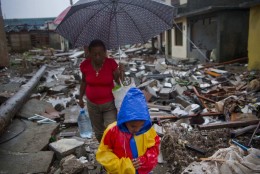 A boy amd a woman walk next to remains of houses destroyed by Hurricane Matthew in Baracoa, Cuba, Wednesday, Oct. 5, 2016. The hurricane rolled across the sparsely populated tip of Cuba overnight, destroying dozens of homes in Cuba's easternmost city, Baracoa, leaving hundreds of others damaged.  (AP Photo/Ramon Espinosa)