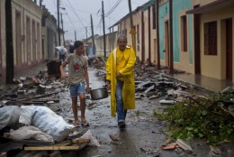 Residents carry food down a street strewn with rubble caused by Hurricane Matthew in Baracoa, Cuba, Wednesday, Oct. 5, 2016. The hurricane rolled across the sparsely populated tip of Cuba overnight, destroying dozens of homes in Cuba's easternmost city, Baracoa, leaving hundreds of others damaged.  (AP Photo/Ramon Espinosa)