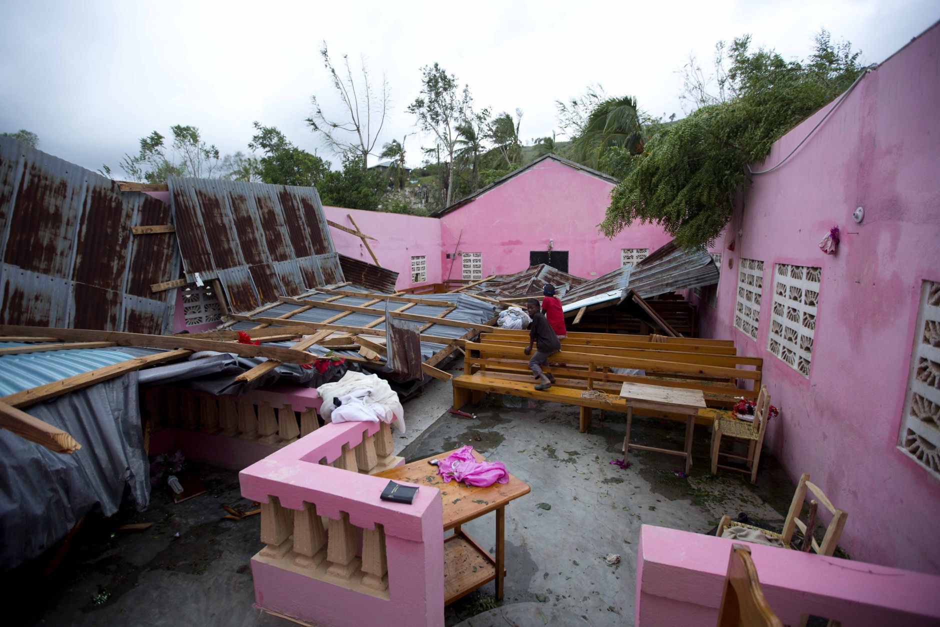 Children sit inside a church damaged by Hurricane Matthew, in Saint-Louis, Haiti, Wednesday, Oct. 5, 2016. Rescue workers in Haiti struggled to reach cutoff towns and learn the full extent of the death and destruction caused by Hurricane Matthew as the storm began battering the Bahamas on Wednesday and triggered large-scale evacuations along the U.S. East Coast. ( AP Photo/Dieu Nalio Chery)