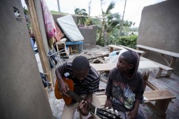 A man sits inside of what is left of his home with his cousin after it was damaged by Hurricane Matthew in Saint-Louis, Haiti, Wednesday, Oct. 5, 2016.  Rescue workers in Haiti struggled to reach cutoff towns and learn the full extent of the death and destruction caused by Hurricane Matthew as the storm began battering the Bahamas on Wednesday and triggered large-scale evacuations along the U.S. East Coast. ( AP Photo/Dieu Nalio Chery)
