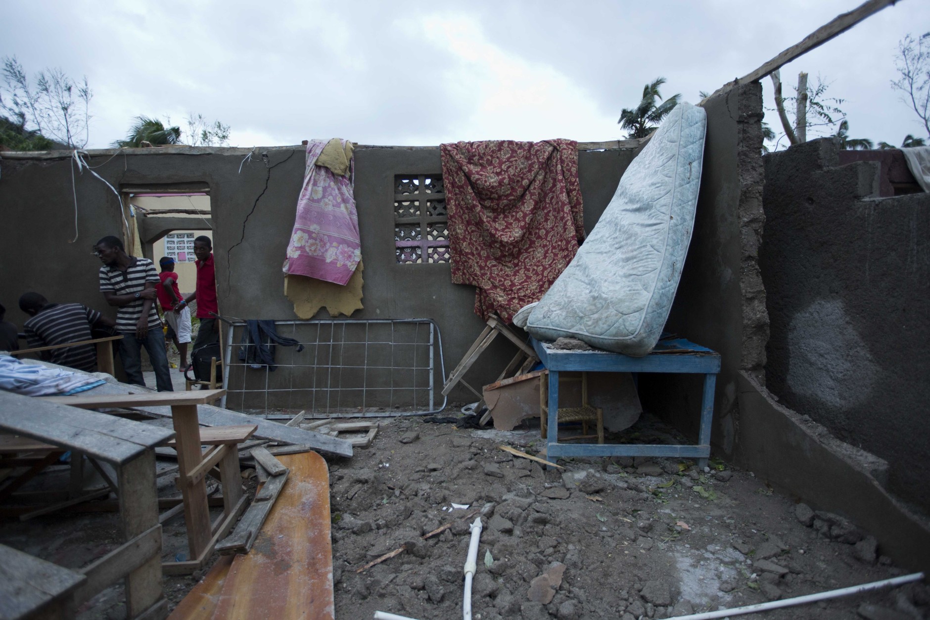Residents walk into a destroyed home after it was damaged by Hurricane Matthew in Saint-Louis, Haiti, Wednesday, Oct. 5, 2016. Rescue workers in Haiti struggled to reach cutoff towns and learn the full extent of the death and destruction caused by Hurricane Matthew as the storm began battering the Bahamas on Wednesday and triggered large-scale evacuations along the U.S. East Coast. ( AP Photo/Dieu Nalio Chery)