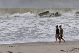 A couple walks along the shoreline after Hurricane Matthew passed off shore, Friday, Oct. 7, 2016, in Jupiter, Fla.  Matthew was downgraded to a Category 3 hurricane overnight with the strongest winds of 120 mph just offshore as the storm pushed north, threatening hundreds of miles of coastline in Florida, Georgia and South Carolina.  (AP Photo/Wilfredo Lee)