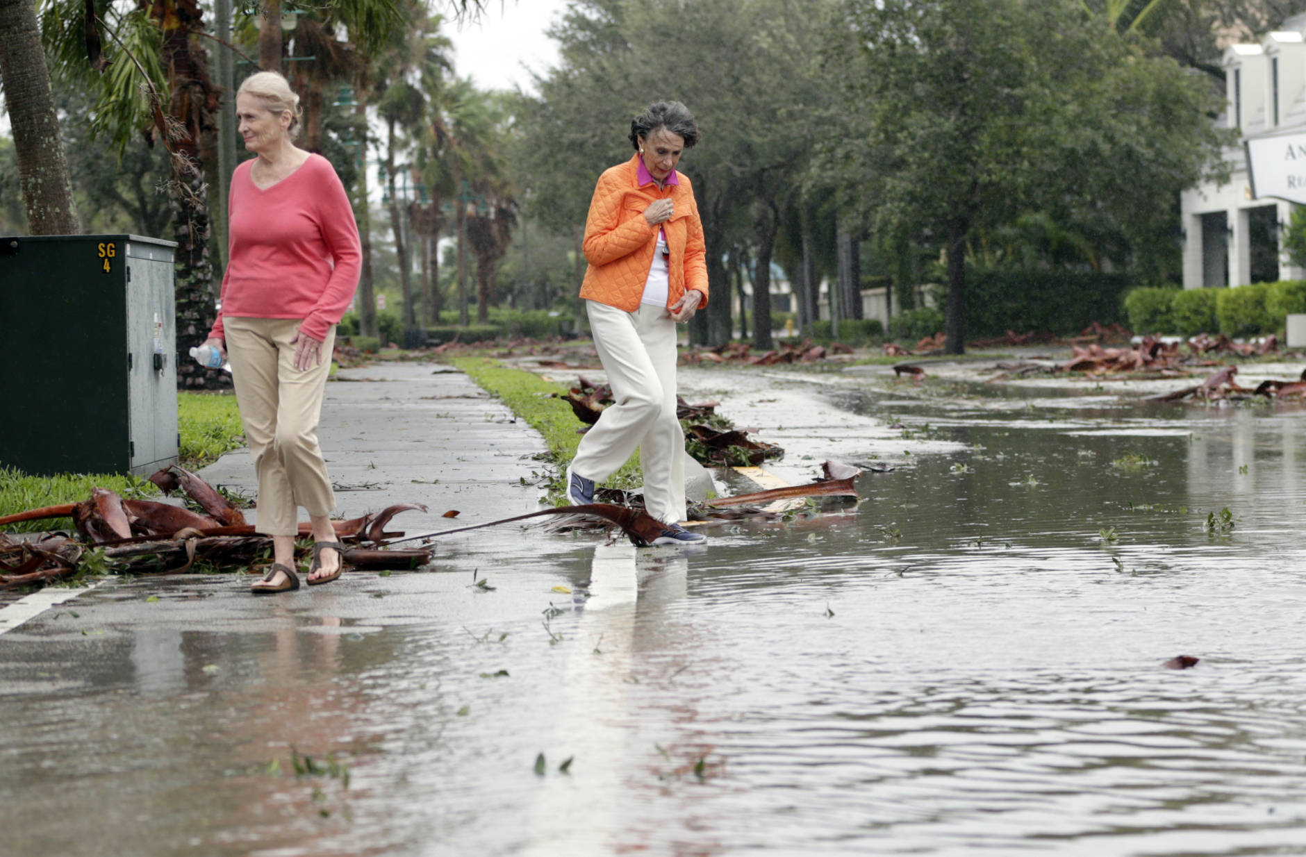 Sherry McMahon, left, and Joan Maddy, right, assess damage from Hurricane Matthew as they walk along a flooded street in a residential neighborhood along the Indian River, Friday, Oct. 7, 2016, in Vero Beach, Fla. Matthew was downgraded to a Category 3 hurricane overnight with the strongest winds of 120 mph just offshore as the storm pushed north, threatening hundreds of miles of coastline in Florida, Georgia and South Carolina.   (AP Photo/Lynne Sladky)