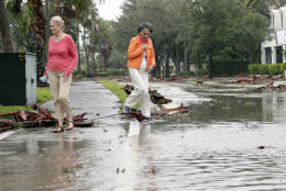 Sherry McMahon, left, and Joan Maddy, right, assess damage from Hurricane Matthew as they walk along a flooded street in a residential neighborhood along the Indian River, Friday, Oct. 7, 2016, in Vero Beach, Fla. Matthew was downgraded to a Category 3 hurricane overnight with the strongest winds of 120 mph just offshore as the storm pushed north, threatening hundreds of miles of coastline in Florida, Georgia and South Carolina.   (AP Photo/Lynne Sladky)