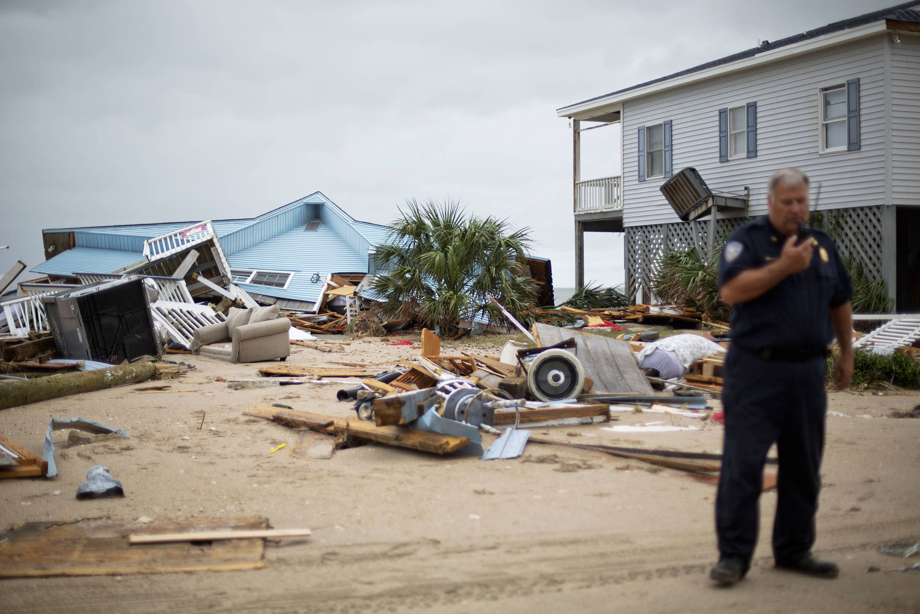 The remnants of a home leveled by Hurricane Matthew sit along the beachfront as Chief of Police George Brothers talks on the radio after Hurricane Matthew hit the tiny beach community of Edisto Beach, S.C., Saturday, Oct. 8, 2016. (AP Photo/David Goldman)