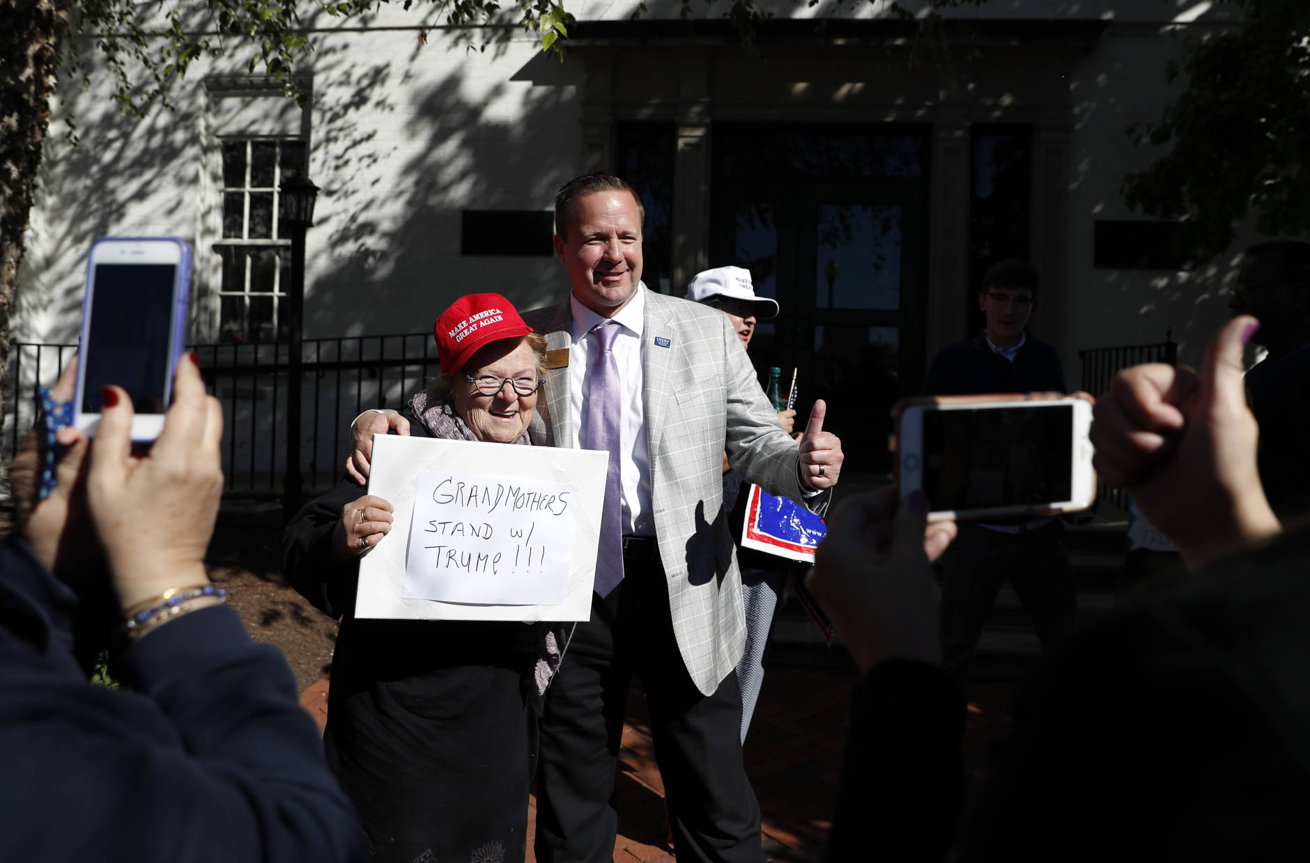 Corey Stewart, chairman of Republican presidential candidate Donald Trump's Virginia campaign, right, gives the thumbs-up as he poses for a photo with Trump supporter Heidi Saba with her sign that reads "Grandmothers Stand w/Trump!!!" outside the Republican National Committee Headquarters in Washington, Monday, Oct. 10, 2016. Stewart and Virginia Women for Trump gathered in support of Trump.  (AP Photo/Carolyn Kaster)