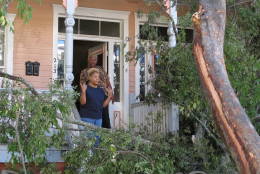 Sharon Kelsey, front, and her cousin, Pamela Williams, stand on the front port of the Victorian home in Savannah, Ga., where Kelsey lives in a first floor apartment Monday, Oct. 10, 2016. A large tree crashed across the front of the house as Hurricane Matthew raked the Georgia coast over the weekend. Matthew did extensive damage to the signature tree canopy in Savannah.  (AP Photo/Russ Bynum)