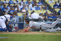 Washington Nationals' Ryan Zimmerman, right, scores past Los Angeles Dodgers catcher Yasmani Grandal on a sacrifice fly by Chris Heisey during the ninth inning in Game 3 of baseball's National League Division Series in Los Angeles, Monday, Oct. 10, 2016. (AP Photo/Mark J. Terrill)