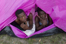 Young men whose home was destroyed by Hurricane Matthew peer out of a tent as they awake for the day in the courtyard of a school where they have sought shelter, in Port Salut, Haiti, Monday, Oct. 10, 2016. Nearly a week after the storm smashed into southwestern Haiti, some communities along the southern coast have yet to receive any assistance, leaving residents who have lost their homes and virtually all of their belongings struggling to find shelter and potable water.(AP Photo/Rebecca Blackwell)