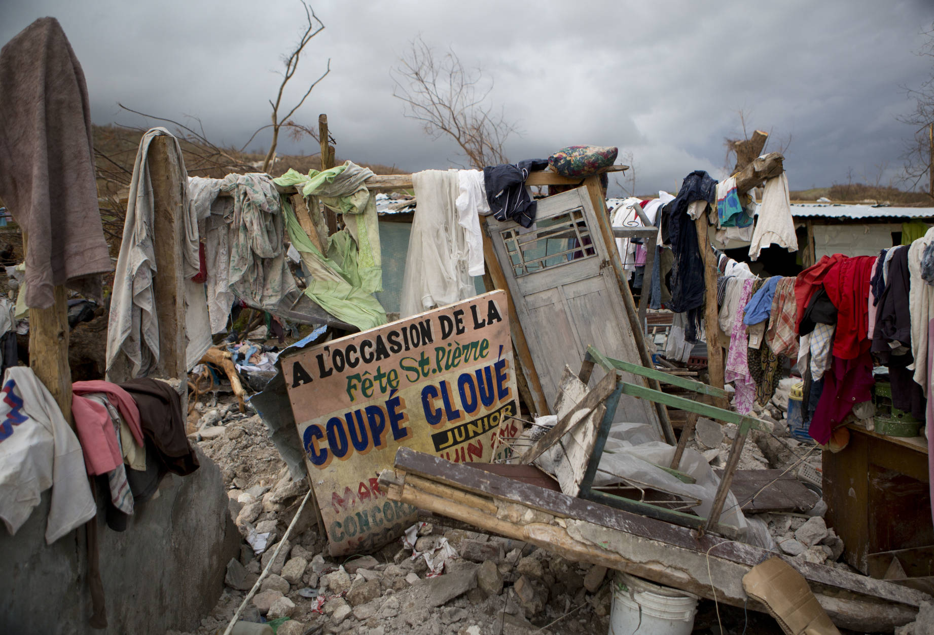 A sign in French announcing a music concert sits among salvaged clothes drying on the remains of a home destroyed by Hurricane Matthew in Port-a-Piment, Haiti, Monday, Oct. 10, 2016. Nearly a week after the storm smashed into southwestern Haiti, some communities along the southern coast have yet to receive any assistance, leaving residents who have lost their homes and virtually all of their belongings struggling to find shelter and potable water. (AP Photo/Rebecca Blackwell)