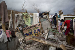A sign in French announcing a music concert sits among salvaged clothes drying on the remains of a home destroyed by Hurricane Matthew in Port-a-Piment, Haiti, Monday, Oct. 10, 2016. Nearly a week after the storm smashed into southwestern Haiti, some communities along the southern coast have yet to receive any assistance, leaving residents who have lost their homes and virtually all of their belongings struggling to find shelter and potable water. (AP Photo/Rebecca Blackwell)