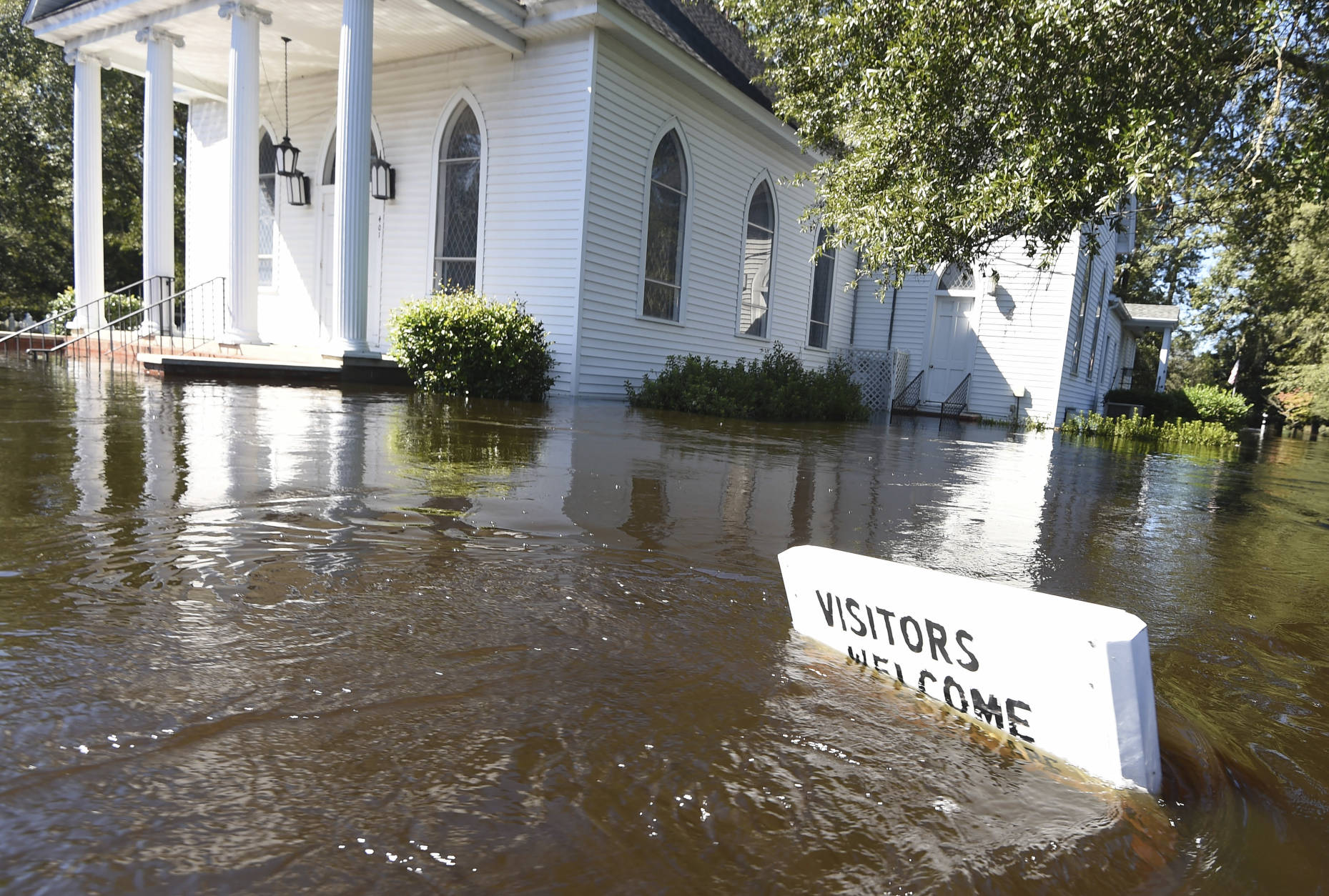 A welcome sign is submerged in floodwaters in front of the Nichols Methodist Church on Tuesday, Oct. 11, 2016, in Nichols, S.C. About 150 people were rescued by boats from flooding in the riverside village of Nichols on Monday. (AP Photo/Rainier Ehrhardt)
