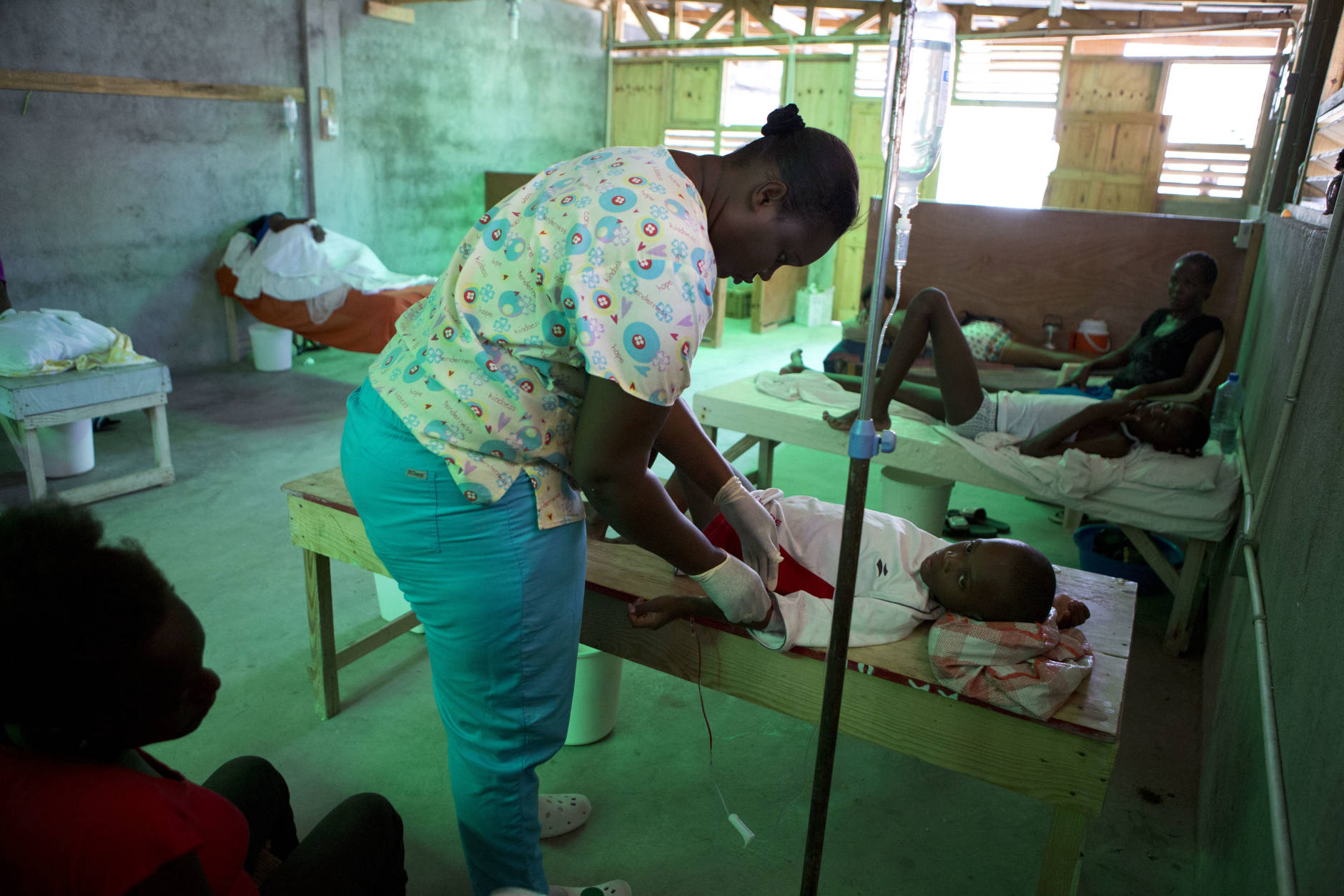 Nurse Mardi Rose Guerline adjusts the IV on 9-year-old Franzy Noel as his mother Geraldine Pierre looks on, in a cholera ward in Les Cayes Haiti, Tuesday, Oct. 11, 2016.  Health authorities have warned that Hurricane Matthew has created conditions that are likely to cause an increase in the deadly waterborne cholera virus.(AP Photo/Rebecca Blackwell)