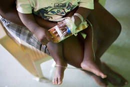 A young child with an IV taped to his hand sits on his mother's lap inside a cholera ward in Les Cayes Haiti, Tuesday, Oct. 11, 2016. Health authorities have warned that Hurricane Matthew has created conditions that are likely to cause an increase in the deadly waterborne cholera virus.(AP Photo/Rebecca Blackwell)