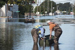Workers with the City of Lumberton use boats to travel down West 5th Street to the city's water treatment plant through floodwaters caused by rain from Hurricane in Lumberton, N.C., Wednesday, Oct. 12, 2016. (AP Photo/Mike Spencer)