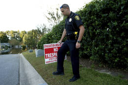 Lt. Mike Broadwell of the Greenville Police Department installs a No Trespassing sign near a neighborhood flooded by water associated with Hurricane Matthew, Wednesday, Oct. 12, 2016, in Greenville, N.C. (AP Photo/Brian Blanco)