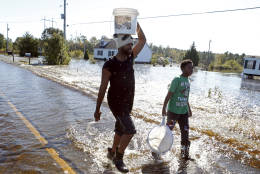 Cedric Blackmon, left, entertains neighbor Jaywuan McMillian, 13, by catching small fish and crawfish on a road covered in floodwater associated with Hurricane Matthew on Thursday, Oct. 13, 2016, in Lumberton, N.C. About 1,200 Lumberton residents had to be evacuated by boat and plucked from their roofs by helicopters as the river crested.  (AP Photo/Brian Blanco)