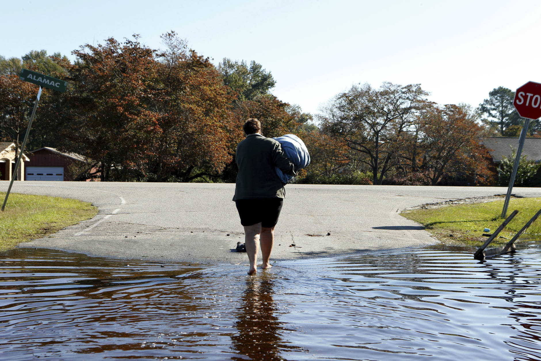 Janet Meier makes her way out of the floodwaters associated with Hurricane Matthew surrounding her home after retrieving a warm blanket and her laptop computer from her home on Thursday, Oct. 13, 2016, in Lumberton, N.C.  About 1,200 Lumberton residents had to be evacuated by boat and plucked from their roofs by helicopters as the river crested. (AP Photo/Brian Blanco)