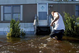 Elmer McDonald braces himself on the handrail to his front steps as makes his way through a strong current in his front yard while returning to his mobile home for the first time to inspect damage caused by floodwaters associated with Hurricane Matthew on Thursday, Oct. 13, 2016, in Lumberton, N.C. About 1,200 Lumberton residents had to be evacuated by boat and plucked from their roofs by helicopters as the river crested; McDonald was one of thousands who evacuated.   (AP Photo/Brian Blanco)