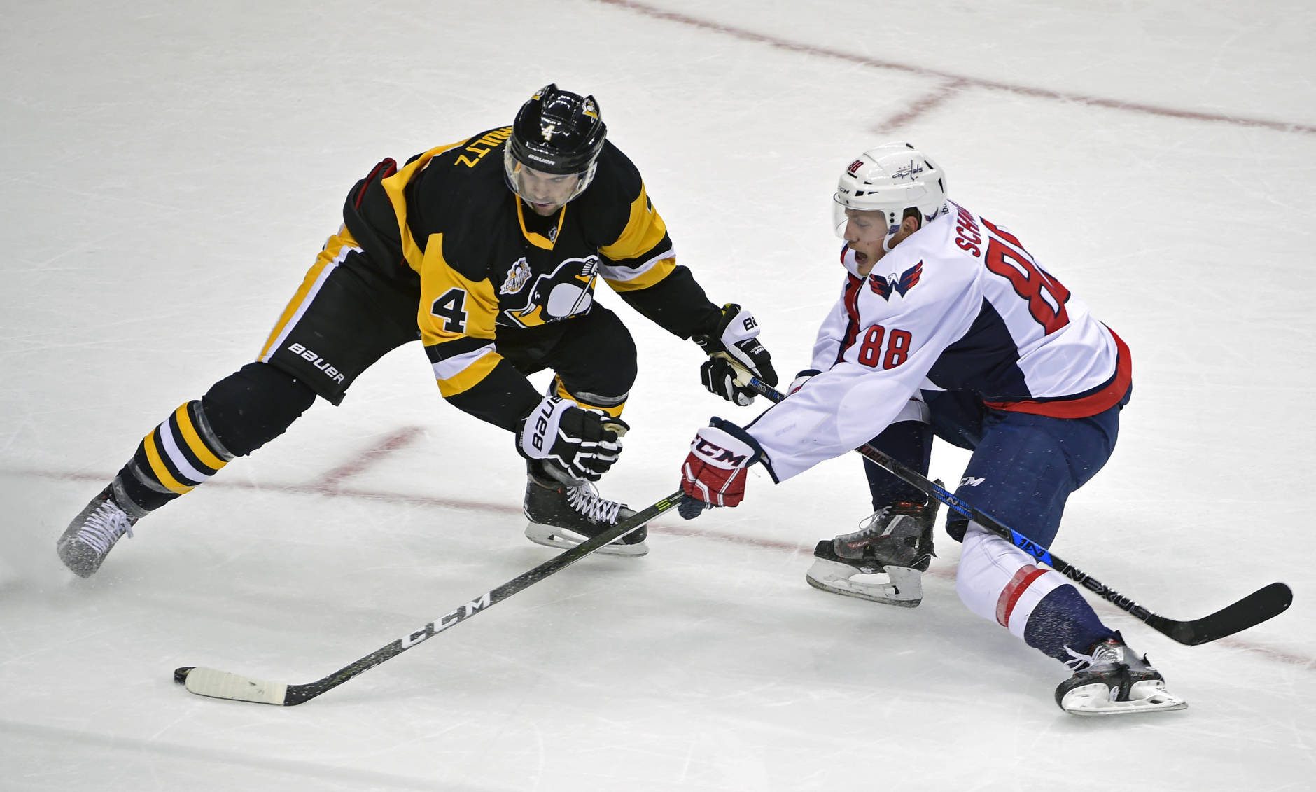 Pittsburgh Penguins defenseman Justin Schultz (4) tries to poke-check the puck off the stick of Washington Capitals defenseman Nate Schmidt (88) during the third period of an NHL hockey game Thursday, Oct. 13, 2016, in Pittsburgh. (AP Photo/Fred Vuich)