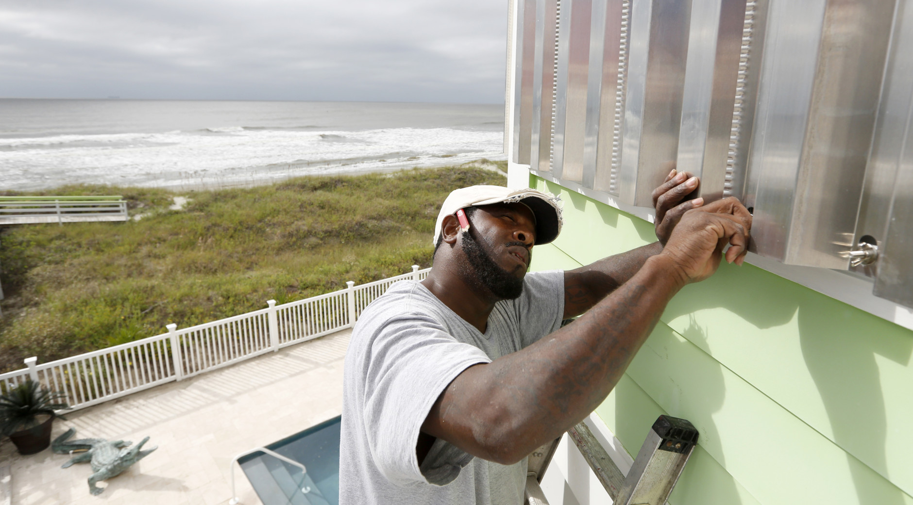 Dimitri Pinckney installs hurricane shutters in advance of Hurricane Matthew on the Isle of Palms, S.C., Wednesday, Oct. 5, 2016. Hurricane Matthew is expected to affect the South Carolina coast by the weekend. Gov. Nikki Haley announced Tuesday that, unless the track of the storm changes, the state will issue an evacuation order Wednesday to help get 1 million people inland from the coast. (AP Photo/Mic Smith)