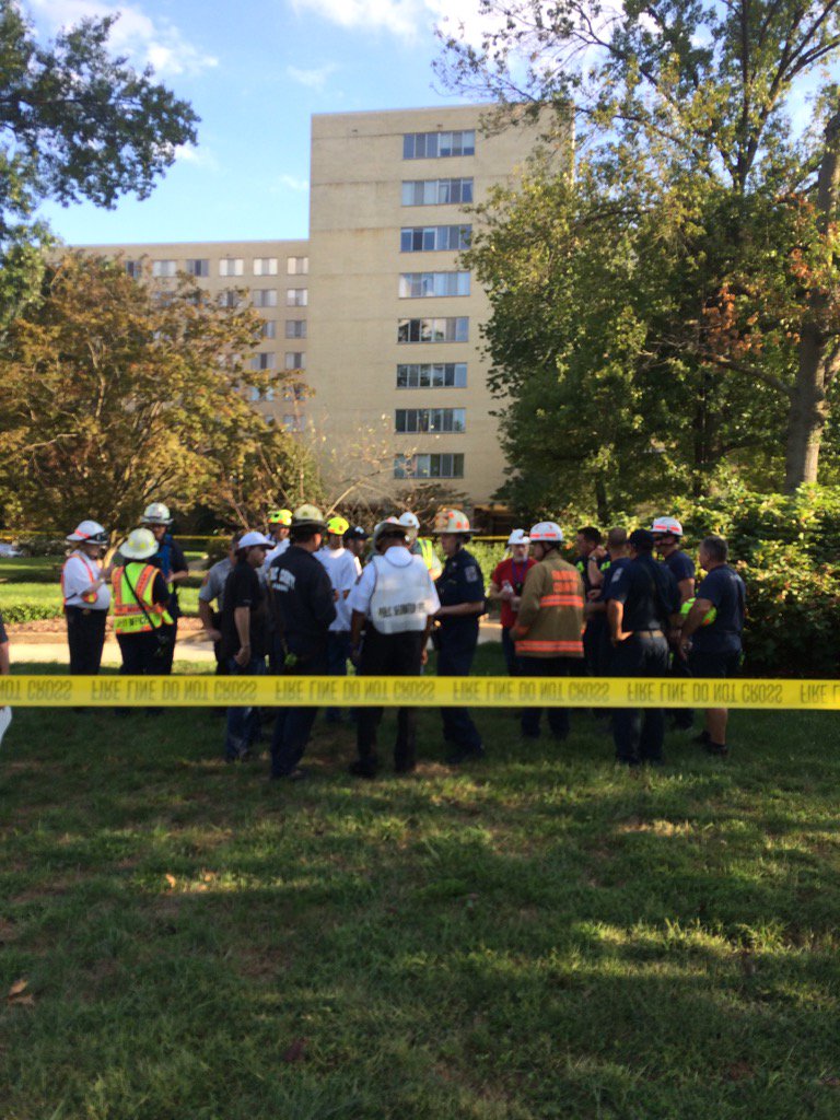 Emergency responders gather outside of the River Towers condo in Alexandria, Va. The nine-story building was evacuated on Sunday, Oct. 2, 2016, due to possible structural damage. (WTOP/Dick UIiano)