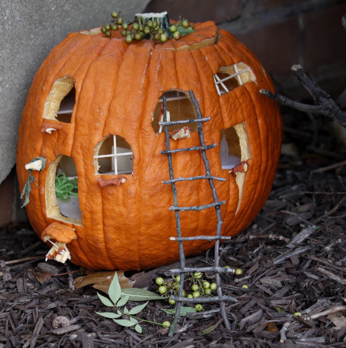 This pumpkin has windows with miniature panes made of toothpicks. Small ledges protrude from the windows and there’s a teeny tiny ladder made out of twigs leaning up against one of the windows. (WTOP/Kate Ryan)
