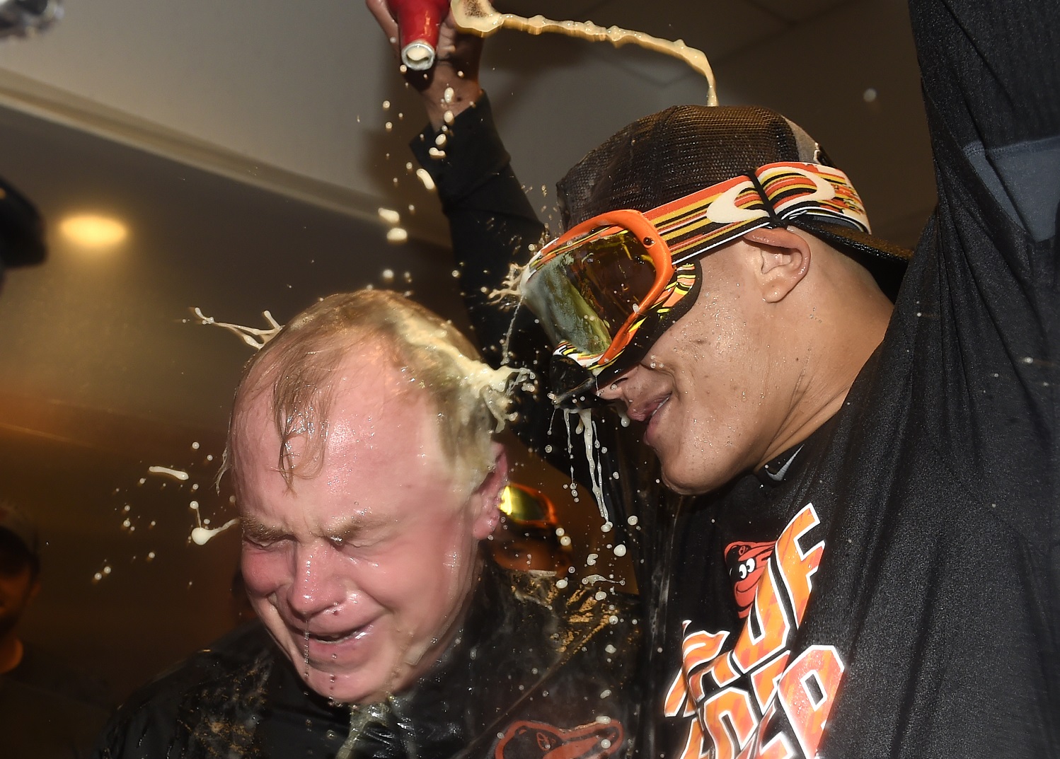 Baltimore Orioles manager Buck Showalter is doused with beer by Manny Machado in the visitors' clubhouse after the Orioles defeated the New York Yankees 5-2 in a baseball game to go to the playoffs , Sunday, Oct. 2, 2016, in New York. (AP Photo/Kathy Kmonicek)