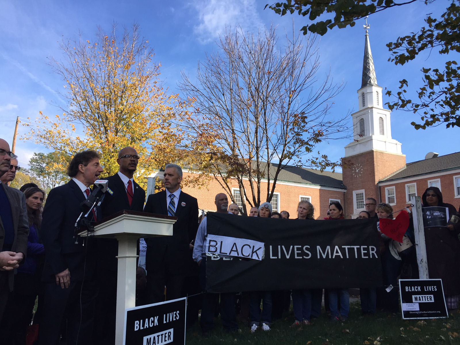 Officials gathered in front of the repaired sign. (WTOP/John Aaron)