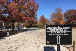 Signs outside the welcome center at Arlington National Cemetery inform pedestrians about screening requirements. (WTOP/John Aaron)