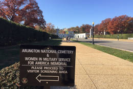 Signs outside the welcome center at Arlington National Cemetery inform pedestrians about screening requirements. (WTOP/John Aaron)