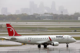 The Minneapolis skyline rises through the rain as an arriving Northwest Airlines jet taxis at Minneapolis-St. Paul International Airport Friday, Oct. 23, 2009. Investigators are looking into a Northwest flight bound for Minneapolis from San Diego which over flew the airport by 150 miles. (AP Photo/Jim Mone)
