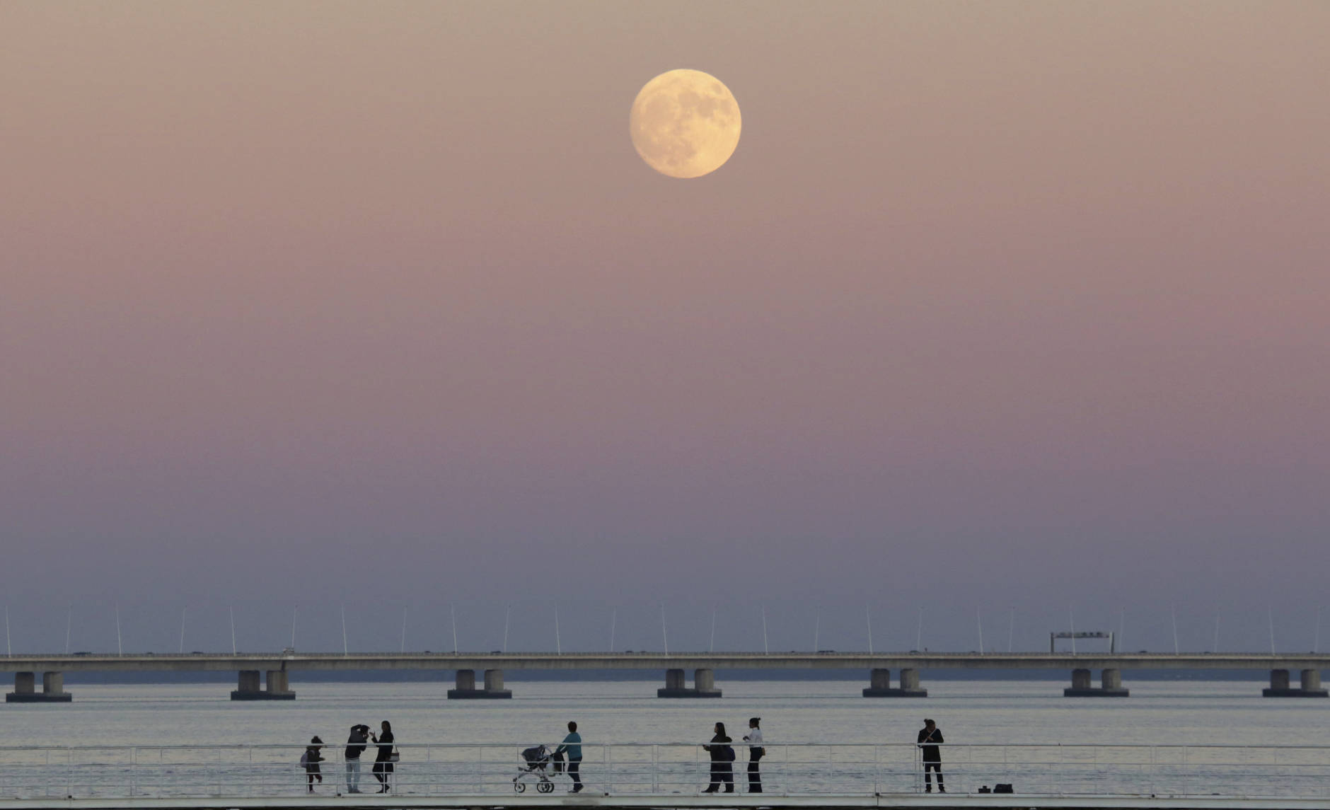 People stroll along the Tagus riverside in Lisbon as the moon rises Sunday, Nov. 13 2016. The so-called Supermoon on Nov. 14, 2016, will be the closest a full moon will have been to Earth since 1948. (AP Photo/Armando Franca)