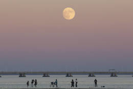 People stroll along the Tagus riverside in Lisbon as the moon rises Sunday, Nov. 13 2016. The so-called Supermoon on Nov. 14, 2016, will be the closest a full moon will have been to Earth since 1948. (AP Photo/Armando Franca)