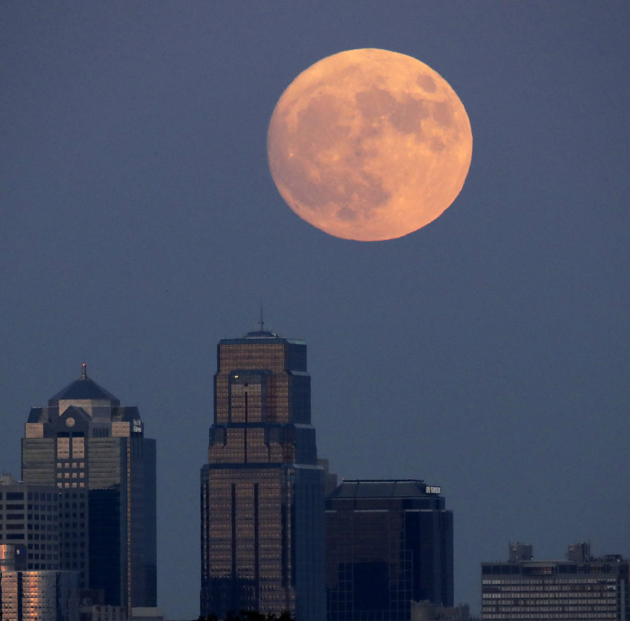 The moon rises beyond downtown buildings Sunday, Nov. 13, 2016, in Kansas City, Mo. Monday's supermoon will be extra super — it will be the closest the moon comes to us in almost 69 years. And it won't happen again for another 18 years. (AP Photo/Charlie Riedel)