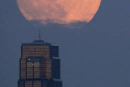 The moon rises beyond downtown buildings Sunday, Nov. 13, 2016, in Kansas City, Mo. Monday's so-called supermoon will be extra super - it will be the closest the moon comes to us in almost 69 years. And it won't happen again for another 18 years. (AP Photo/Charlie Riedel)