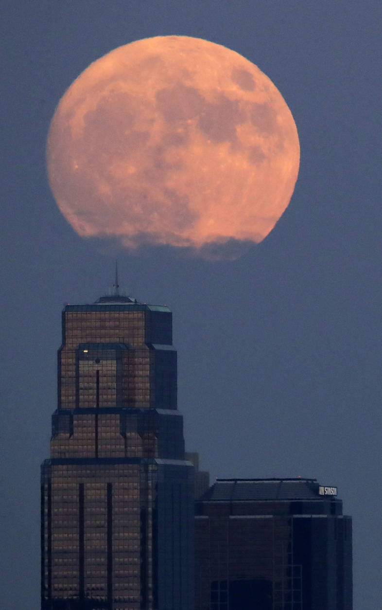 The moon rises beyond downtown buildings Sunday, Nov. 13, 2016, in Kansas City, Mo. Monday's so-called supermoon will be extra super - it will be the closest the moon comes to us in almost 69 years. And it won't happen again for another 18 years. (AP Photo/Charlie Riedel)