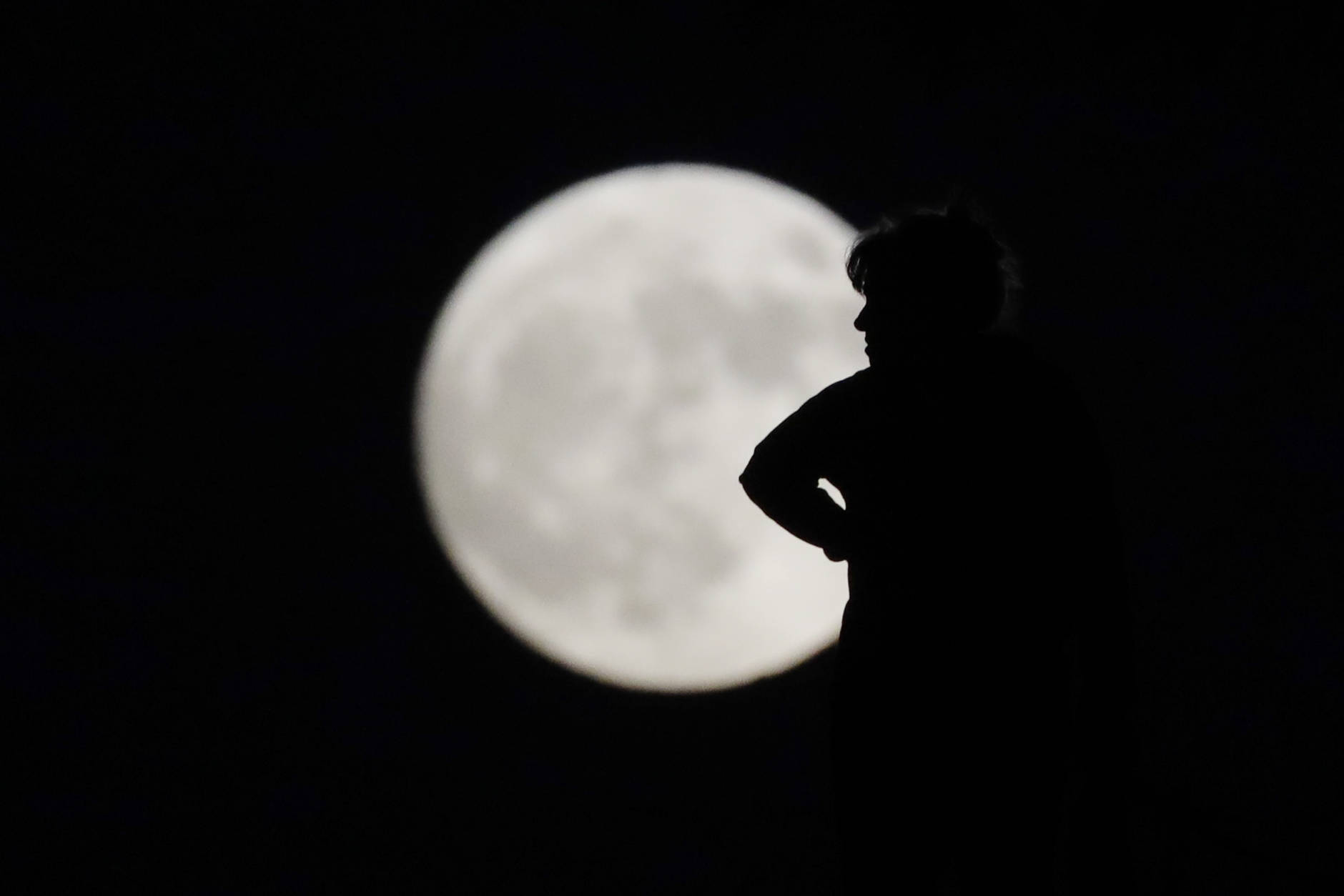 A woman is silhouetted against the moon while walking her dog Sunday, Nov. 13, 2016, in La Habra, Calif. Monday's so-called supermoon will be the closest the moon comes to us in almost 69 years. And it won't happen again for another 18 years. (AP Photo/Jae C. Hong)