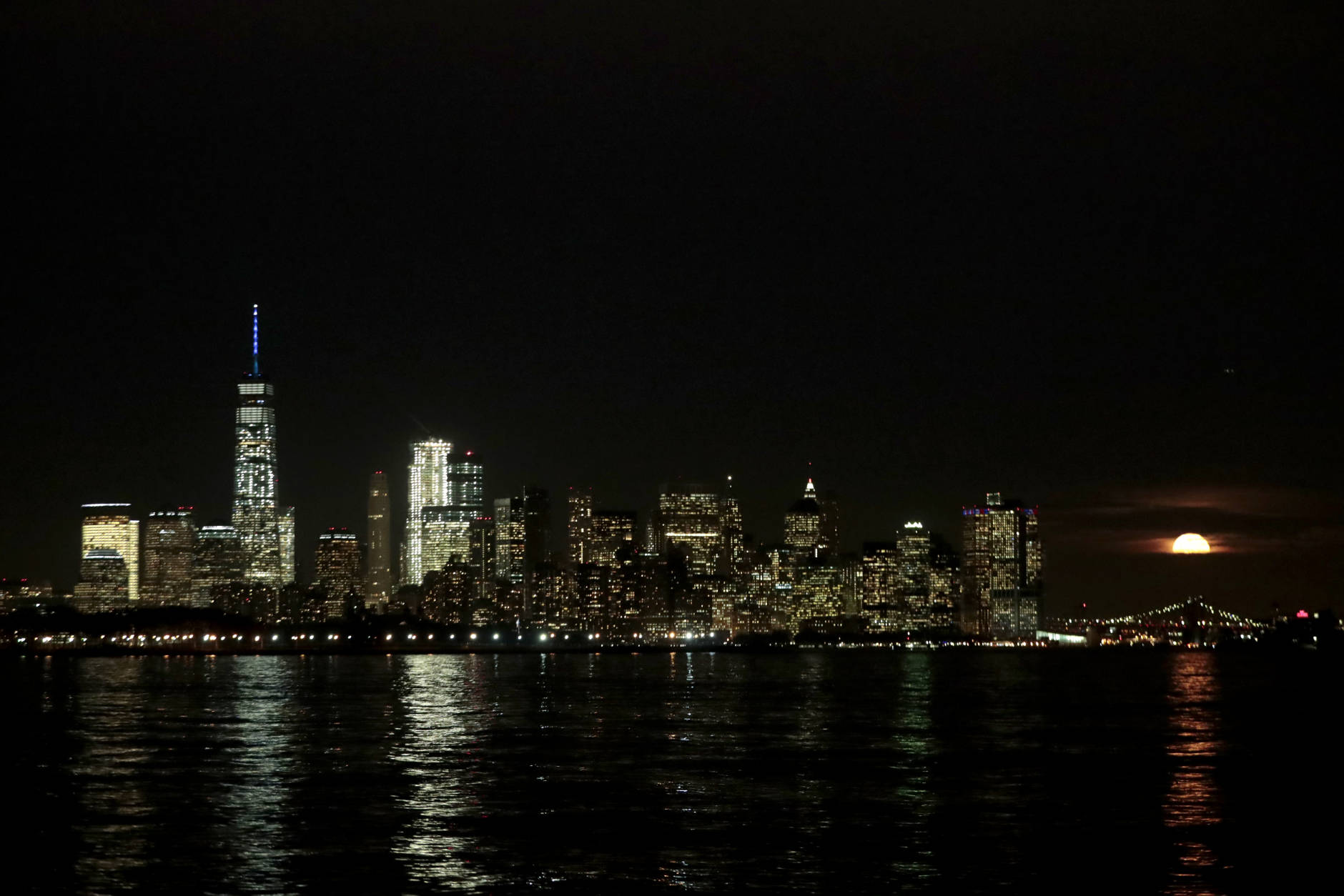 The supermoon, right, rises behind clouds near the Lower Manhattan skyline, seen from the Port Liberte neighborhood of Jersey City, N.J., Monday, Nov. 14, 2016. (AP Photo/Julio Cortez)