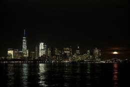 The supermoon, right, rises behind clouds near the Lower Manhattan skyline, seen from the Port Liberte neighborhood of Jersey City, N.J., Monday, Nov. 14, 2016. (AP Photo/Julio Cortez)