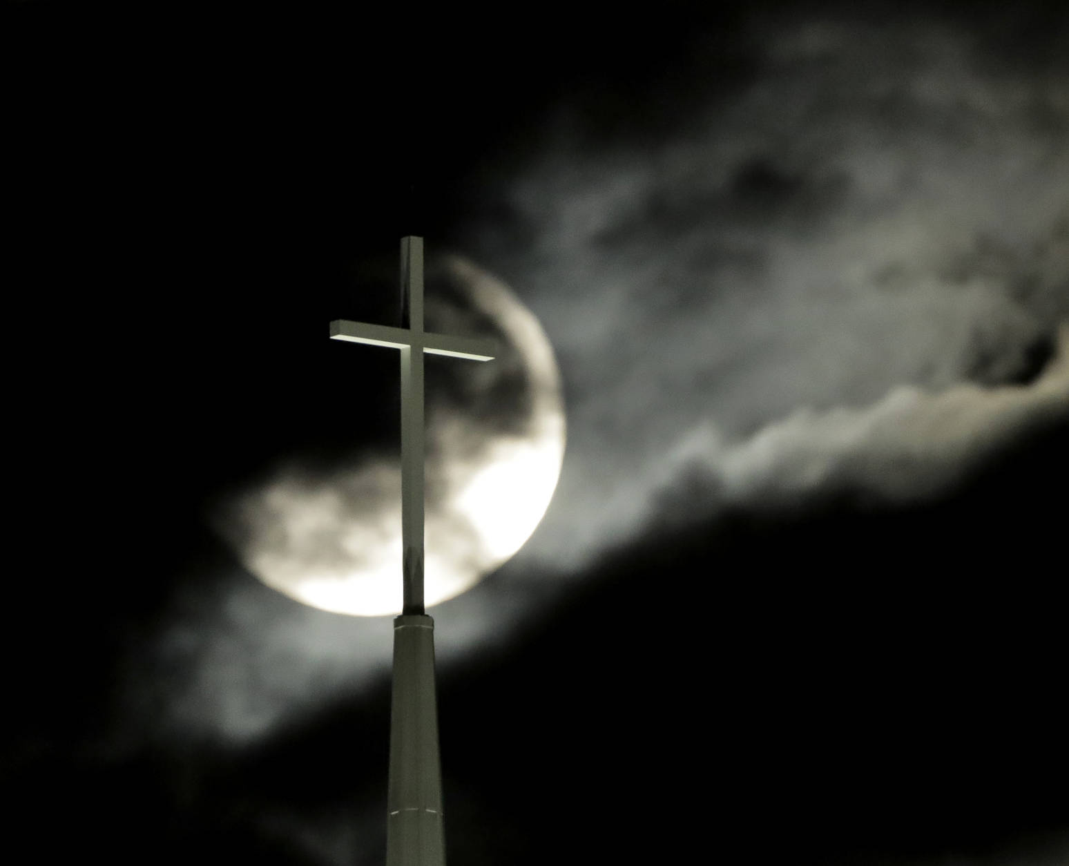 Partially obscured by clouds, a full moon rises behind the cross atop Lenexa Baptist Church, Monday, Nov. 14, 2016, in Lenexa, Kan. November's full moon is the brightest since 1948, according to NASA. (AP Photo/Charlie Riedel)