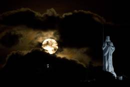 Partially obscured by clouds, a full moon rises behind the monument of Christ of Havana in Havana, Cuba, Monday, Nov. 14, 2016. The brightest moon in almost 69 years is lighting up the sky in a treat for star watchers around the globe. The phenomenon known as the supermoon reached its peak luminescence in North America before dawn on Monday. Its zenith in Asia and the South Pacific was Monday night. (AP Photo/Ramon Espinosa)